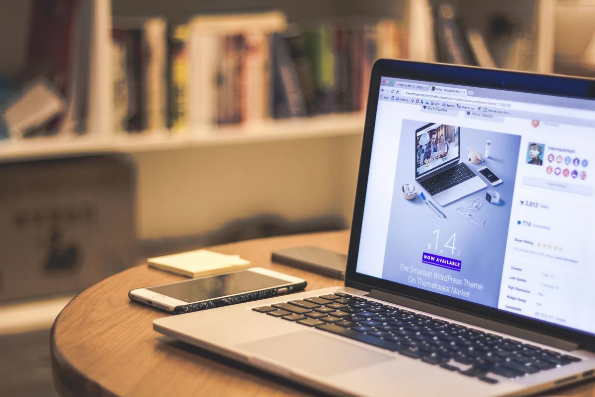 Laptop mit geöffneter Produktseite eines WordPress-Themes auf einem Holztisch