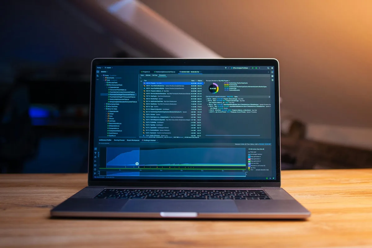 Laptop auf einem Holztisch mit geöffneter Entwicklungsumgebung und Code auf dem Bildschirm